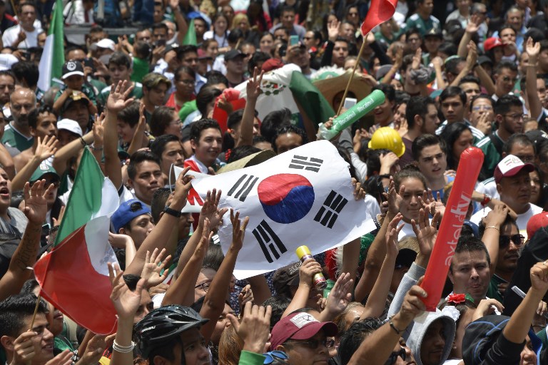 VIVA KOREA! A football fan holds a flag of South Korea as thousands watch the World Cup match between Mexico and Sweden on a screen at the Angel de la Independencia Monument in Mexico City. Photo by Johan Ordonez/AFP   