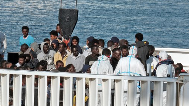 MIGRANTS. Men wait to disembark from the Italian Coast Guard vessel 'Diciotti' following a rescue operation of migrants and refugees at sea on June 13, 2018 in the port of Catania, Sicily. Photo by Giovanni Isolino/AFP 