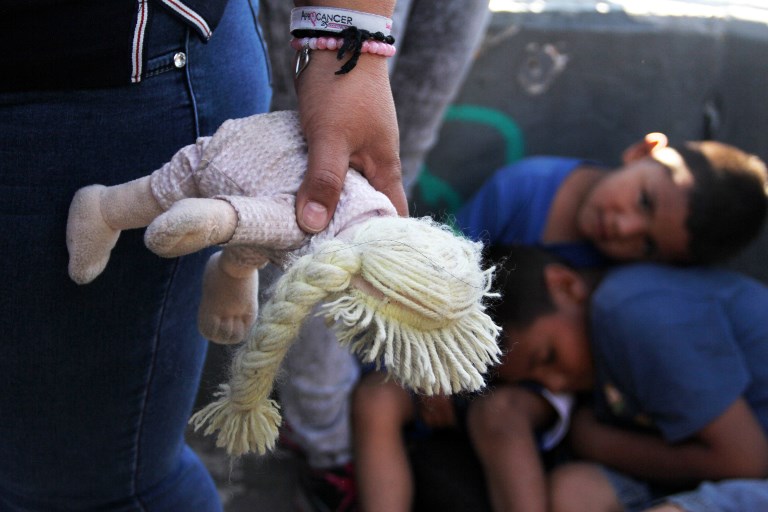 AT THE BORDER. A Mexican woman holds a doll next to children at the Paso Del Norte Port of Entry, in the US-Mexico border in Chihuahua state, Mexico on June 20, 2018. File photo by Herika Martinez/AFP 