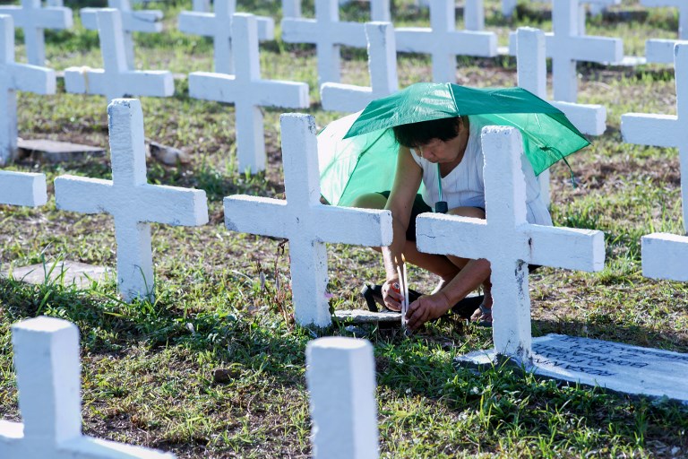 REMEMBER. A woman lights a candle at the grave of a relative at a mass grave for victims of Super Typhoon Haiyan in Tacloban City, Leyte on November 7, 2018. AFP photo 