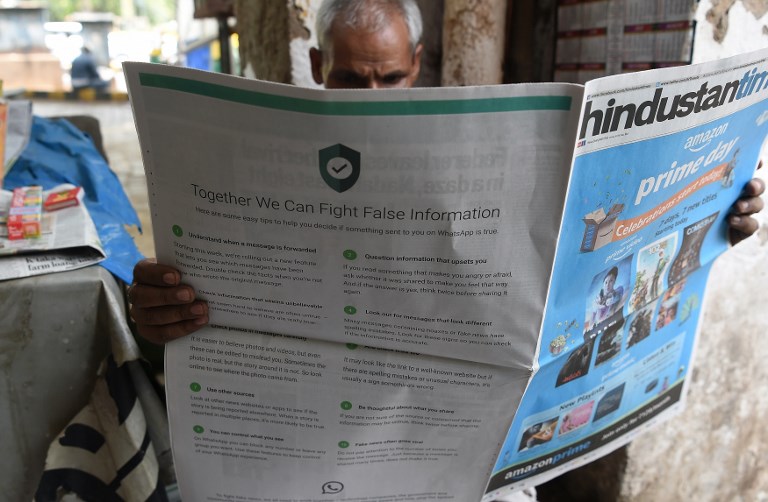 WHATSAPP. This photo illustration shows an Indian newspaper vendor reading a newspaper with a full back page advertisement from WhatsApp intended to counter fake information, in New Delhi on July 10, 2018. Photo by Prakash Singh/AFP 