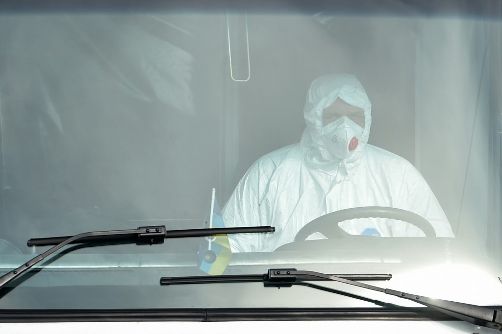 FIRST CASE. In this file photo, a man wearing protective clothing drives a bus carrying evacuees from coronavirus-hit China upon their arrival at an airport in Kharkiv on February 20, 2020. File photo by Sergei Supinsky/AFP 