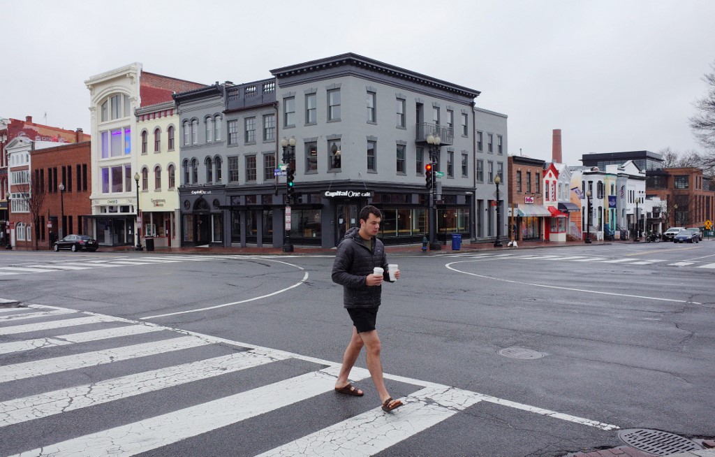 ALMOST EMPTY. A man walks across Wisconsin Avenue in the normally busy shopping district of Georgetown in Washington, DC, on March 23, 2020. Photo by Mandel Ngan/AFP 