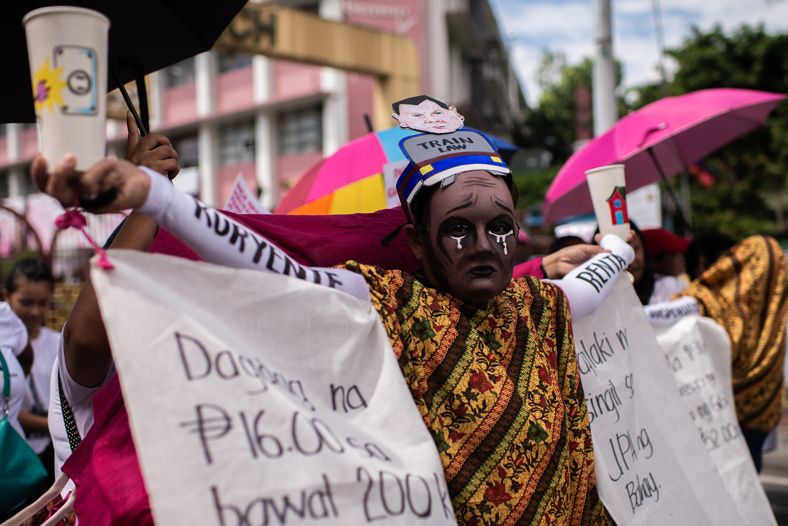 PROTEST VS TRAIN. A Filipino mother masked with a crying face poses like a balancing weighing scale, during the small protest held on Thursday, May 10, in Mendiola, Manila, to appeal to the government to review the TRAIN law. Photo by Eloisa Lopez/Rappler   