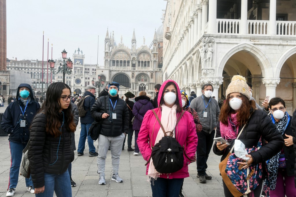 LOCKDOWN. Tourists wearing protective masks visit Venice on February 25, 2020, during the usual period of the Carnival festivities which have been cancelled following an outbreak of the COVID-19 novel coronavirus in northern Italy. Photo by Andrea Pattaro/AFP 