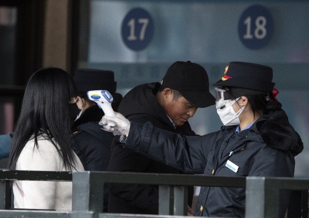 CORONAVIRUS SCARE. Security personnel check the temperature of a passenger wearing a face mask at Beijing Railway Station in China on February 1, 2020. Photo by Noel Celis/AFP 