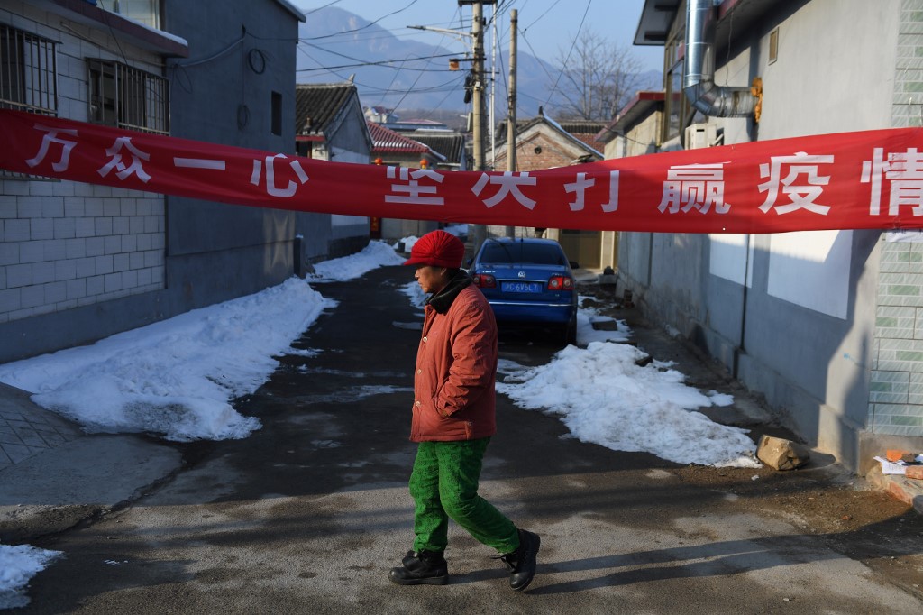 COVID-19. A woman walks past a banner blocking the entrance to a path, part of efforts to prevent the spread of the novel coronavirus, in Heishanzhai village, north of Beijing on February 7, 2020. File photo by Greg Baker/AFP 