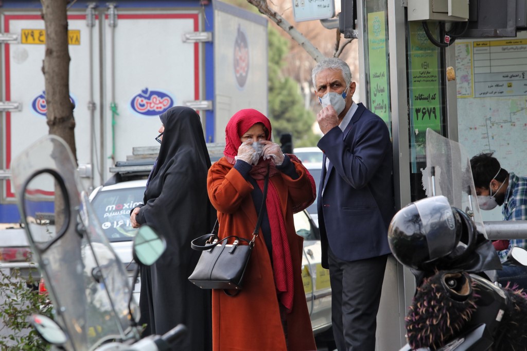 COPING WITH CORONAVIRUS. People wearing protective masks wait along the side of a street in the Iranian capital Tehran on February 24, 2020. Photo by Atta Kenare/AFP 