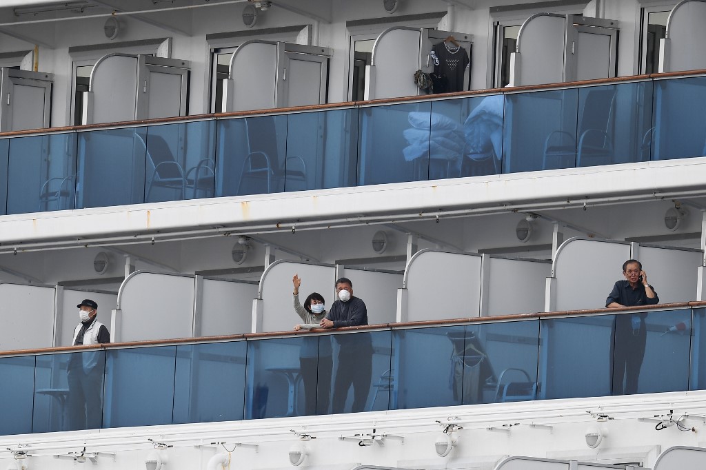 COUPLE. Passengers look out from their balconies on the Diamond Princess cruise ship, with around 3,600 people quarantined onboard due to fears of the new COVID-19 coronavirus, at the Daikoku Pier Cruise Terminal in Yokohama on February 14, 2020. Photo by Charly Triballeau/AFP 