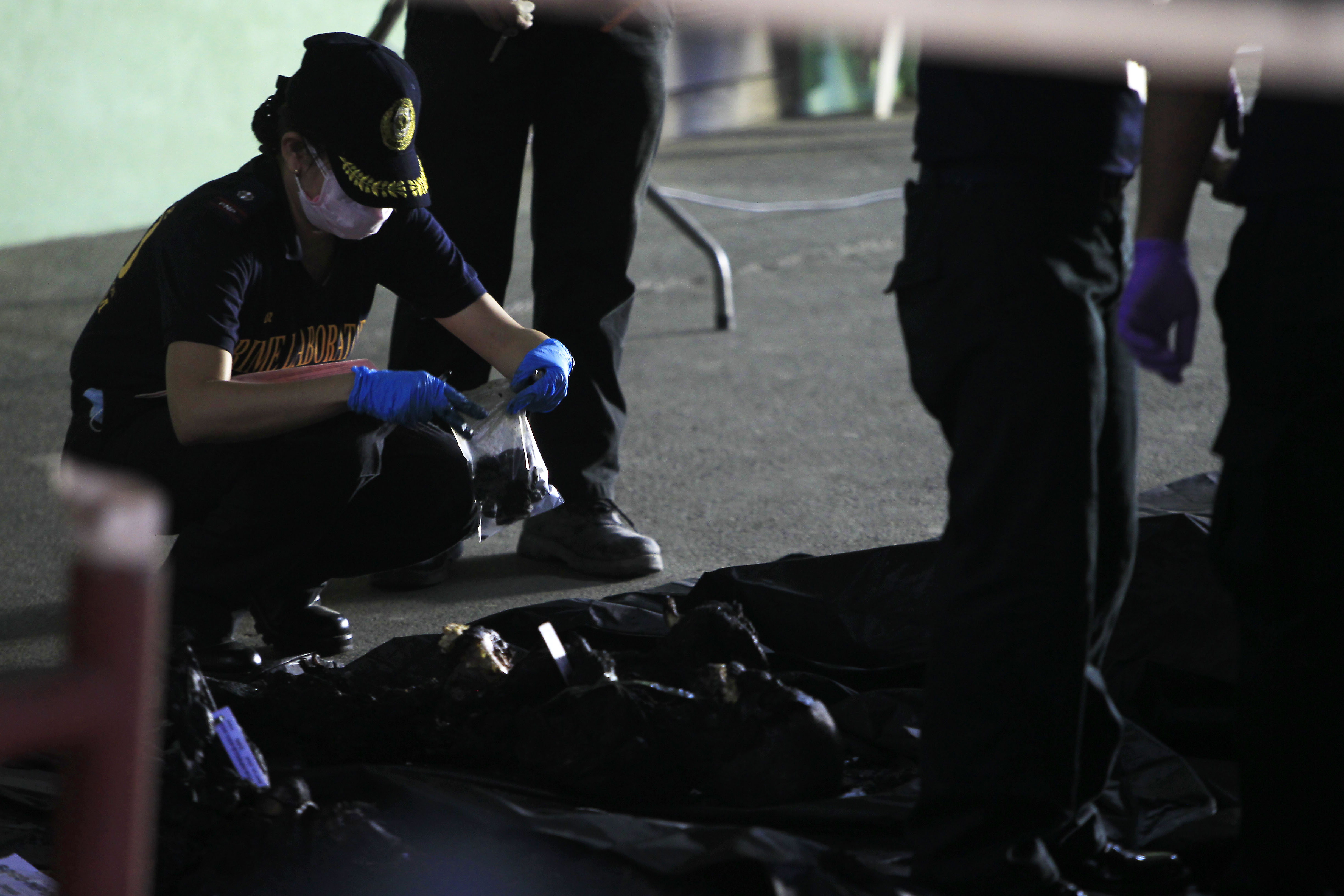 Members of the SOCO examine charred bodies of workers killed in the slipper factory fire as they collect DNA and recognisable marks from the victims at the barangay hall of Maysan, Valenzuela City on May 14, 2015. Photo by Ben Nabong/Rappler 