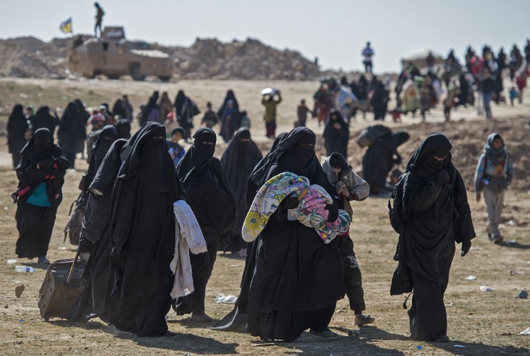 FINAL PUSH. Fully veiled women and children fleeing from the Baghouz area in the eastern Syrian province of Deir Ezzor walk in a field on February 12, 2019 during an operation by the US-backed Syrian Democratic Forces (SDF) to expel hundreds of Islamic State group (IS) jihadists from the region. Photo by Fadel Senna/AFP  