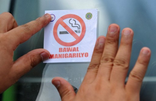NO SMOKING. In this file photo, the Department of Health personnel pastes an anti-smoking sticker on a public utility bus' windshield during the DOH's no smoking campaign on June 17, 2010. File photo by Noel Celis/AFP  