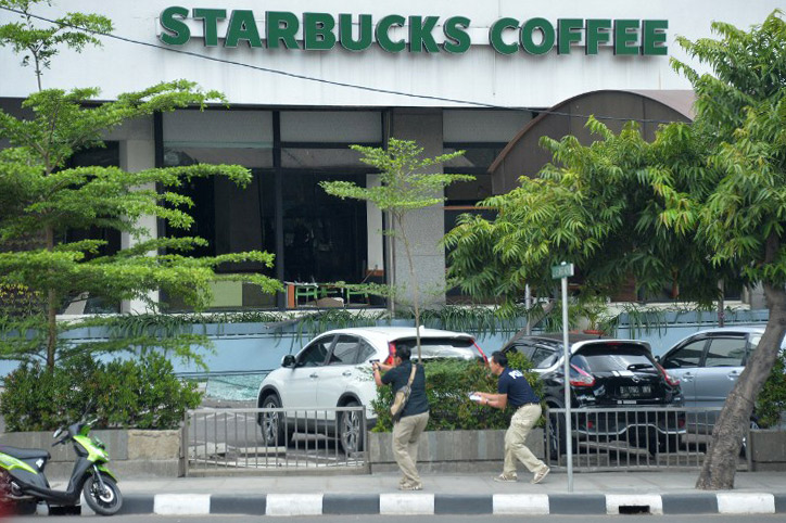SECURITY. Plainclothes police aim their handguns towards suspects outside a cafe after a series of blasts hit the Indonesia capital Jakarta on January 14, 2016. Bay Ismoyo/AFP 
