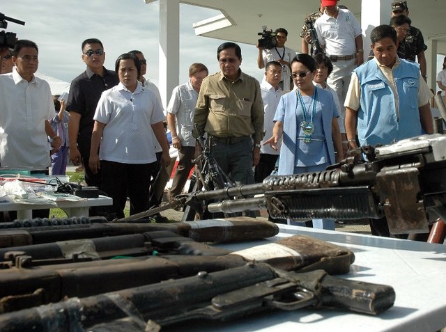 PEACE. Jesus Dureza (center) accompanies former president Gloria Arroyo (2nd R) as she inspects the firearms surrendered by communist rebels to the 4th Infantry Division of the Philippine Army on June 18, 2008. AFP photo   