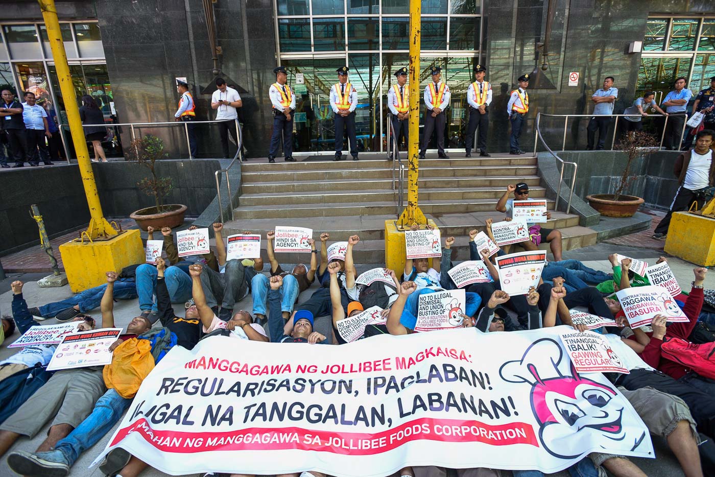 DIE-IN PROTEST. Laid-off agency workers contracted by Jollibee Foods Corporation (JFC) stage a protest in front of the fastfood's main corporate headquarters in Pasig City on June 28, 2018. Photo by Maria Tan/Rappler  