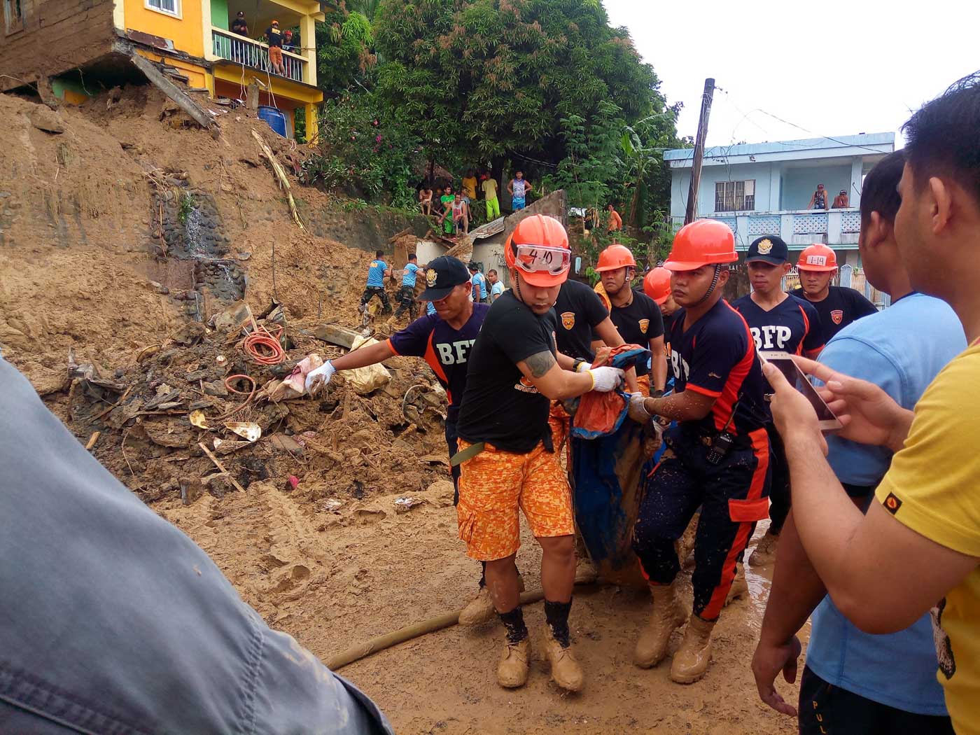 RETRIEVED BODY. Police officers carry a new found body buried in a landslide in Barangay Sugod in Tiwi, Albay on Sunday. Photo by Mavic Conde/Rappler 