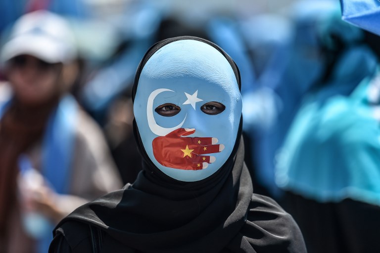 REMEMBERING THE 2009 RIOTS. A demonstrator wearing a mask painted with the colors of the flag of East Turkestan and a hand bearing the colors of the Chinese flag attends a protest of supporters of the mostly Muslim Uighur minority and Turkish nationalists to denounce China's treatment of ethnic Uighur Muslims during a deadly riot in July 2009 in Urumqi, in front of the Chinese consulate in Istanbul, on July 5, 2018. Photo by Ozan Kose/AFP  