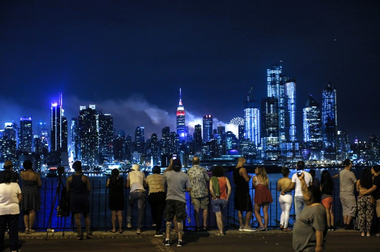 US INDEPENDENCE DAY. People look at the New York skyline lit by the annual Macy's 4th of July fireworks on July 4, 2018, in Weehawken, New Jersey. Photo by Kena Betancur/AFP    