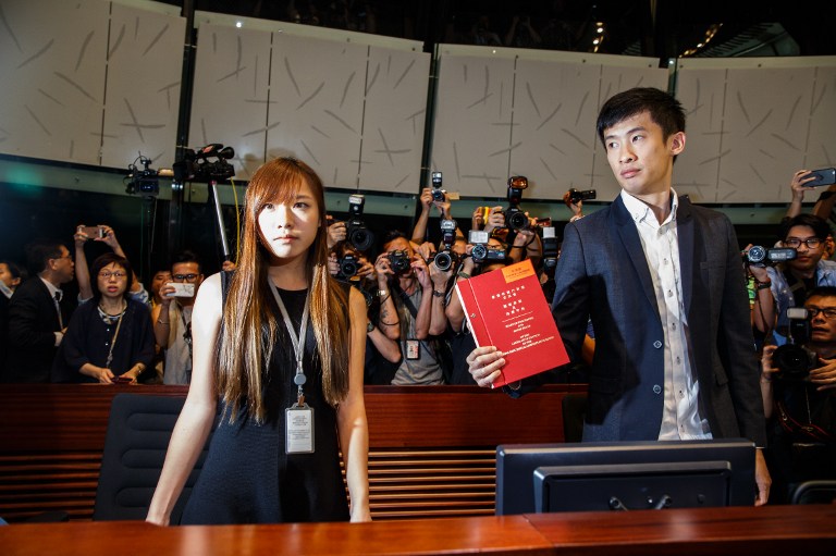 Newly-elected lawmaker Baggio Leung Chung-hang (R) holds up a Legislative Council book next to fellow pro-independence lawmaker Yau Wai-ching (L) while being surrounded by the press after arriving at the Legislative Council main chamber in Hong Kong on October 26, 2016. Anthony Wallace/AFP 