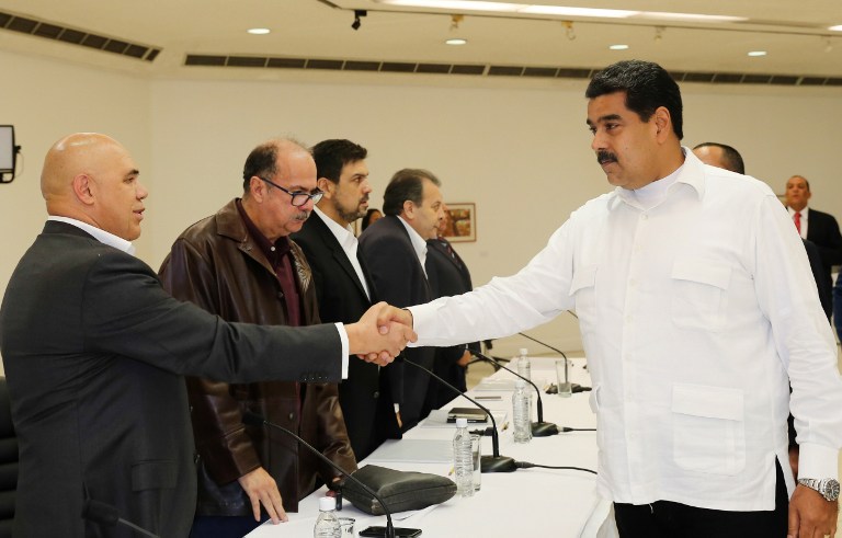 This handout picture released by Venezuelan Presidency shows Venezuela's President Nicolas Maduro (R) shaking hands with Venezuelan opposition spokesman Jesus Torrealba, before a meeting between Venezuela's government and opposition leaders for Vatican-backed talks, in a bid to settle the country's deepening political crisis, in Caracas on October 30, 2016. Venezuelan Presidency/Handout/AFP 