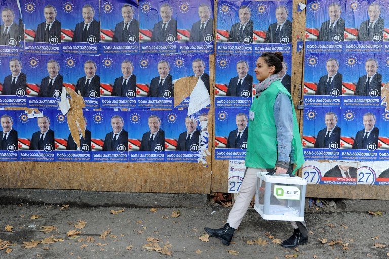 An official walks with a ballot box along election posters during the second round of parliamentary elections in Tbilisi on October 30, 2016. Vano Shlamov/AFP 