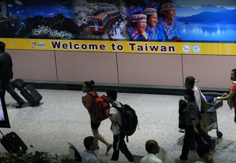 RULES EASED. Tourists walk past an official tourism advertisement on arrival at Taoyuan airport, northern Taiwan, on April 27, 2011. File photo by Sam Yeh/AFP 