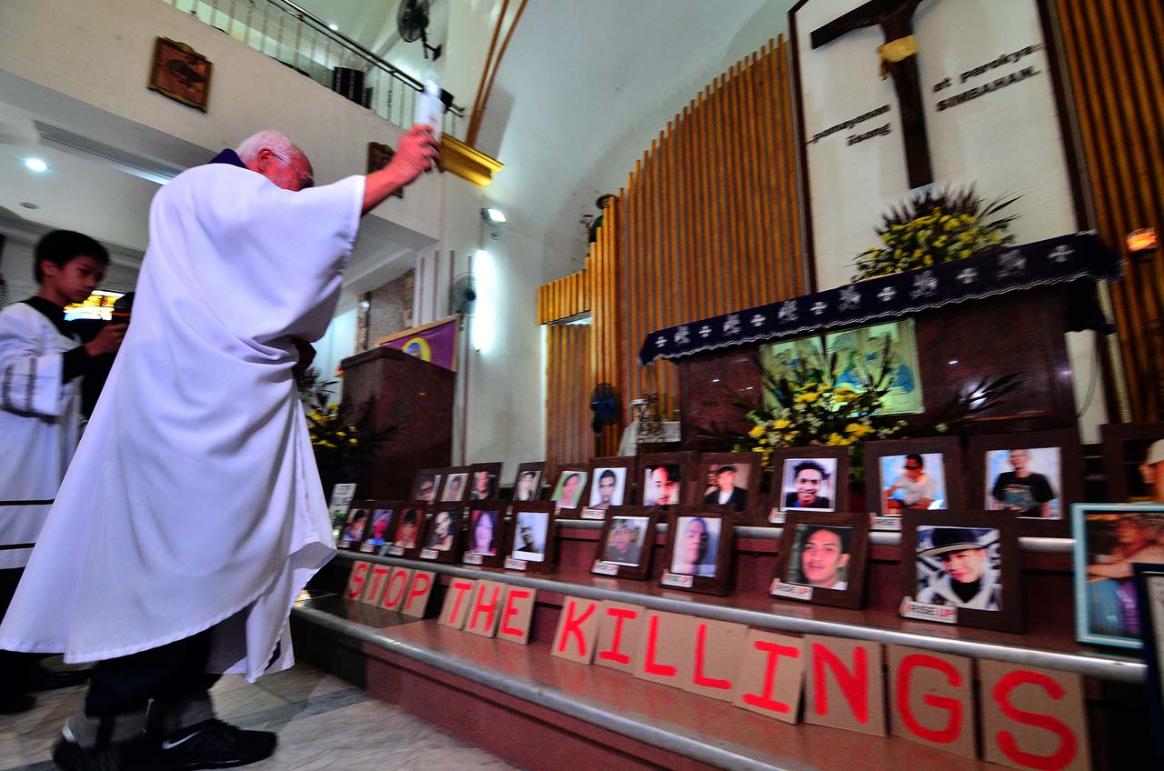 IN MEMORY. Fr Gilbert Billena blesses the photos of victims of drug-related killings at a Mass at the San Isidro Labrador Parish in  Bagong Silangan, Quezon City, on October 31, 2017. Photo by Maria Tan 