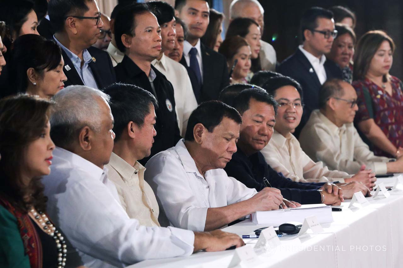 TAX REFORM. President Rodrigo Duterte is flanked by lawmakers as he signs the Tax Reform for Acceleration and Inclusion law. Malacañang photo