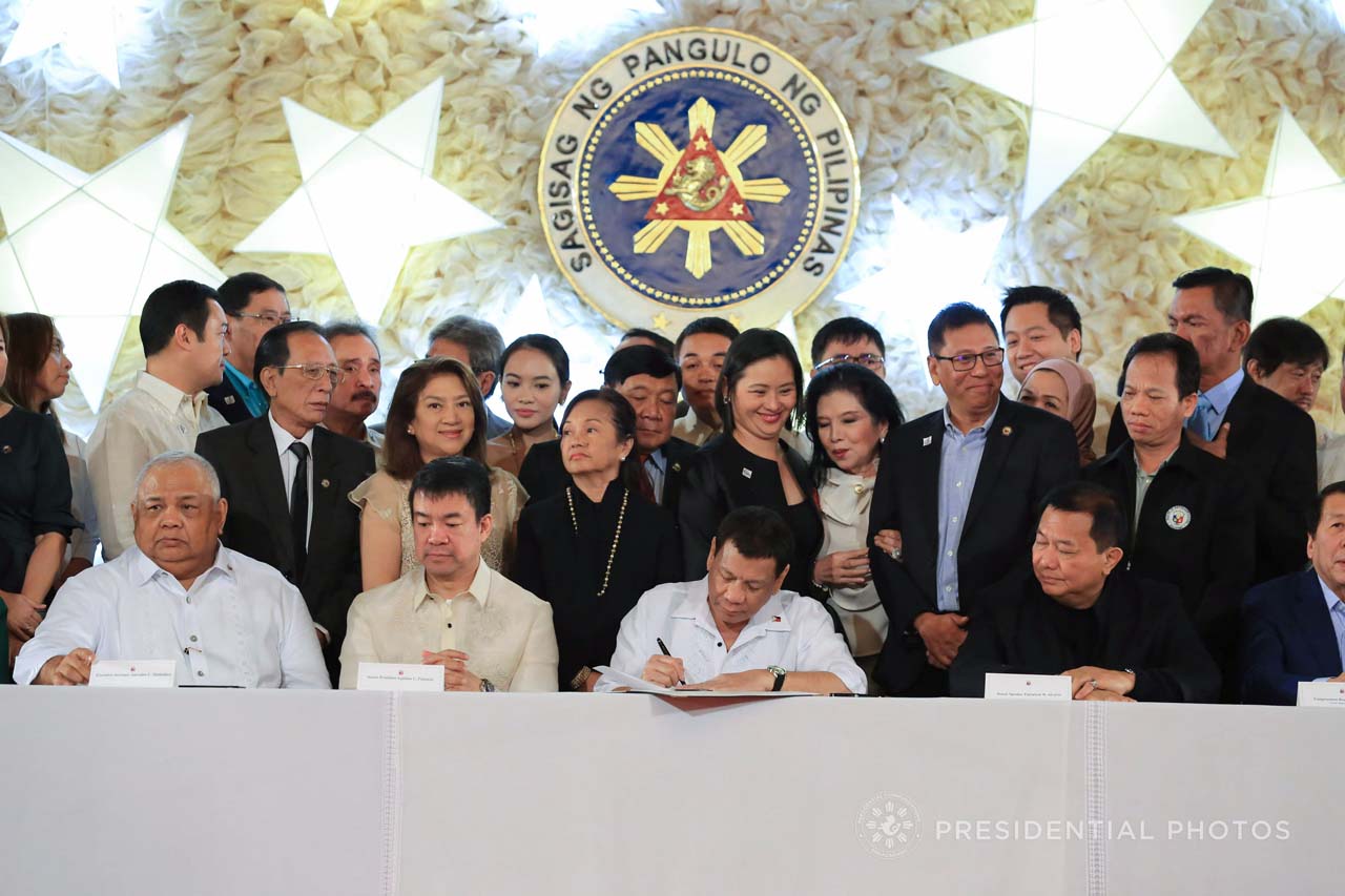2018 BUDGET. President Rodrigo Duterte signs the 2018 budget into law. He is flanked by members of the Philippine Congress. Photo by Albert Alcain/Presidential Photo 