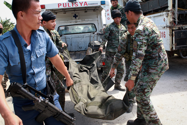 BODY COUNT. Police carry a body bag of one of their comrades during a retrieval operation on January 26, 2015, in Mamasapano, Maguindanao province.     