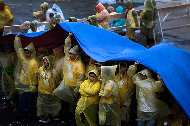 Typhoon Yolanda victims shield themselves from the rain during a mass officiated by Pope Francis at the DZR airport in Tacloban City on January 17, 2015. Photo by Dennis Sabangan/EPA 