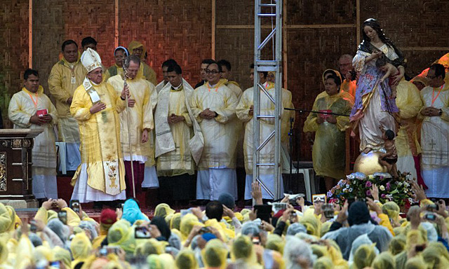 CONSOLING SURVIVORS. Pope Francis in a raincoat holds a Mass in Tacloban City on January 17, 2015. Photo by Johannes Eiselle/AFP 