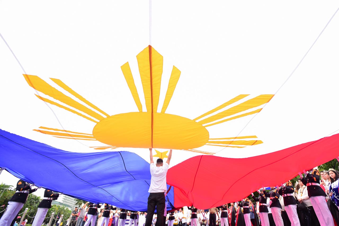 INDEPENDENCE DAY. A man helps keep the Philippine flag from hitting the ground during the Independence Day celebration in Manila on June 12, 2018. Photo by Maria Tan/Rappler 