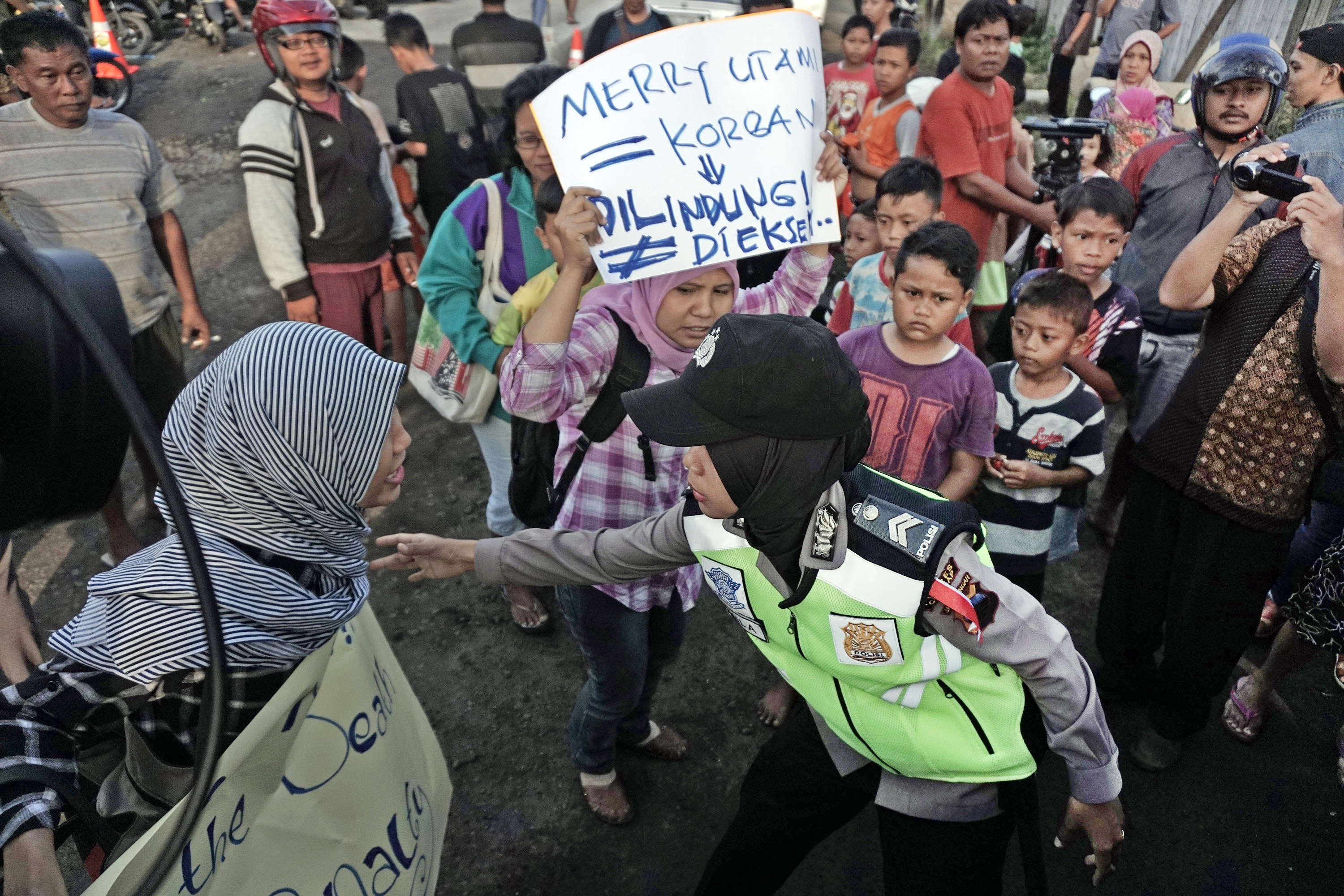 Petugas mengamankan pendemo dari Koalisi Perempuan Indonesia Kabupaten Cilacap, yang menolak hukuman mati terhadap Merry Utami di depan Dermaga Penyeberangan Wijayapura, Cilacap, Jateng, pada 28 Juli 2016. Foto oleh Idhad Zakaria/Antara 
