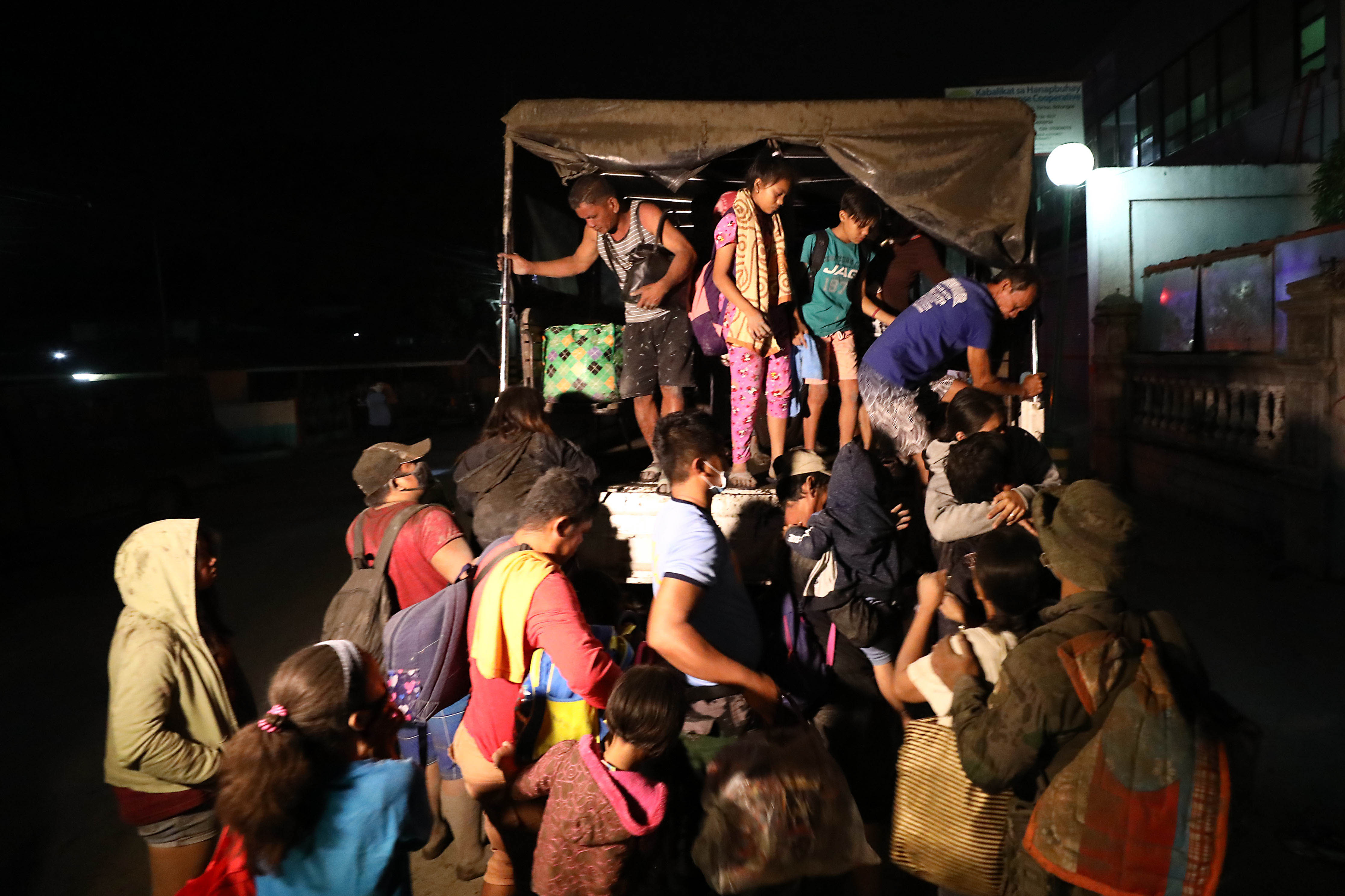 EVACUATION. Police help evacuees get on trucks of the DPWH and PNP as they evacuate during the first day of the eruption of Taal volcano in Batangas on Monday, January 13. Photo by Ben Nabong/Rappler  