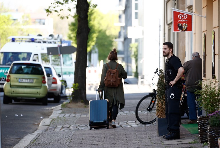 LEAVING. A policeman looks on as a woman pulls a suitcase through a street that is to be evacuated due to the disposal of a World War II bomb close to the Hauptbahnhof main railway station in Berlin's Mitte district on April 20, 2018. Photo by Odd Andersen/AFP 