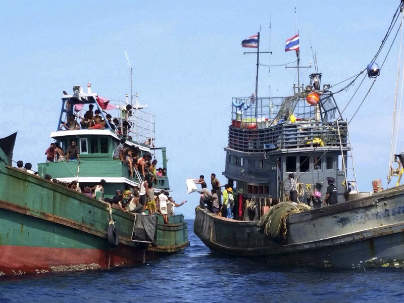 BOAT PEOPLE. Ethnic Muslim Rohingya migrants, believed to have come from Myanmar and Bangladesh (left), receive food, water and other aid supplies from a Thai fishing boat (right) in the Andaman Sea close to Malaysia, southern Thailand, on May 14, 2015. Photo by EPA  