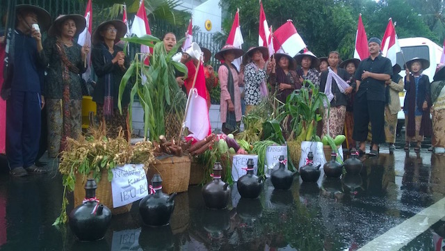 Meski hujan turun, warga Kendeng tetap melanjutkan penyampaian aspirasi di depan Kantor Kedutaan Besar Jerman, Jakarta, pada Senin, 16 Mei 2016. Mereka membawa tanaman dan kendi sebagai lambang bumi. Foto: Print Wulung. 