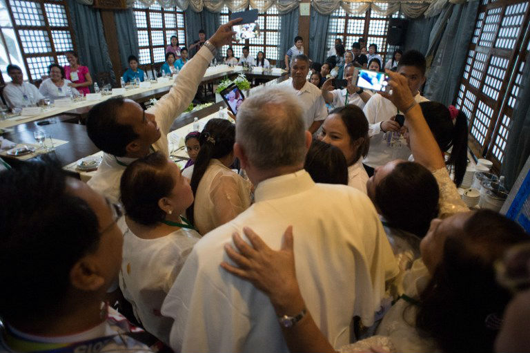 PRIVATE MEETING. In this behind-the-scenes meeting, Pope Francis poses for 'selfies' with survivors of Super Typhoon Yolanda (Haiyan) on January 17, 2015, as part of his trip to the Philippines. Photo by Osservatore Romano/AFP 