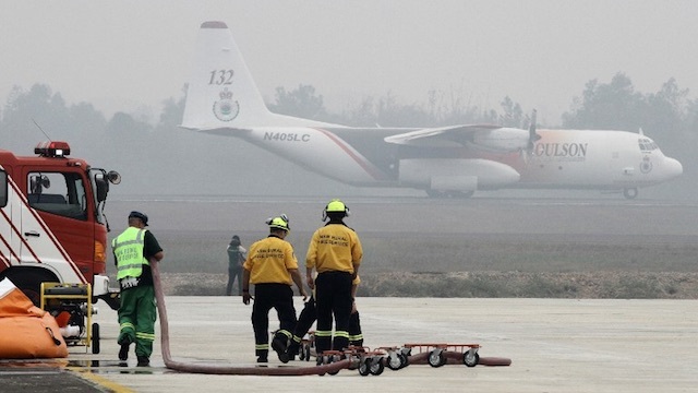 HUGE OPERATION. Australian firefighters prepare their equipment blanketed by haze while their Hercules air tanker plane prepares to take off for its first water bombing mission from Palembang Air Base. Photo by AFP