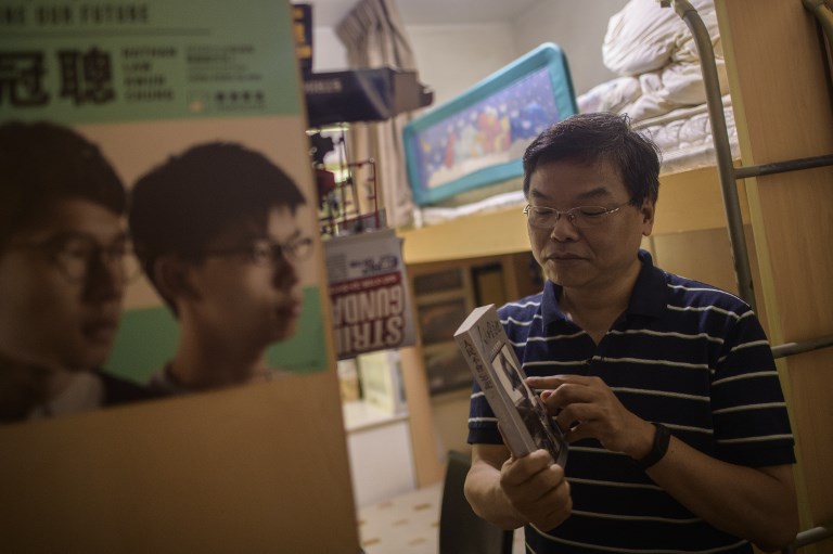 JOSHUA WONG. Roger Wong, father of jailed pro-democracy activist Joshua Wong, holds an original copy of a book which he gave to his son, 'People Will Not Forget,' as he stands in Joshua's room during an interview with AFP at their family home in Hong Kong on October 12, 2017. Photo by Anthony Wallace/AFP 