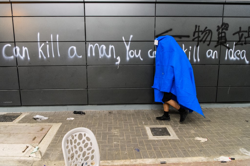 CAN"T KILL AN IDEA. An anti-government protester uses a blanket as he walks to ambulances outside the campus of the Hong Kong Polytechnic University (PolyU) after being barricaded inside for days on November 20, 2019. Photo by Anthony Wallace/AFP   