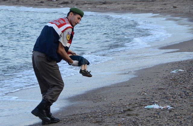 TENGGELAM. Seorang polisi Turki membawa tubuh anak imigran asal Suriah di pantai di Bodrum, daerah selatan Turki, pada 2 September 2015. Perahu yang ditumpangi anak ini tenggelam dalam perjalanan menuju ke Pulau Kos, Yunani. Foto oleh Dogan News Agency/AFP