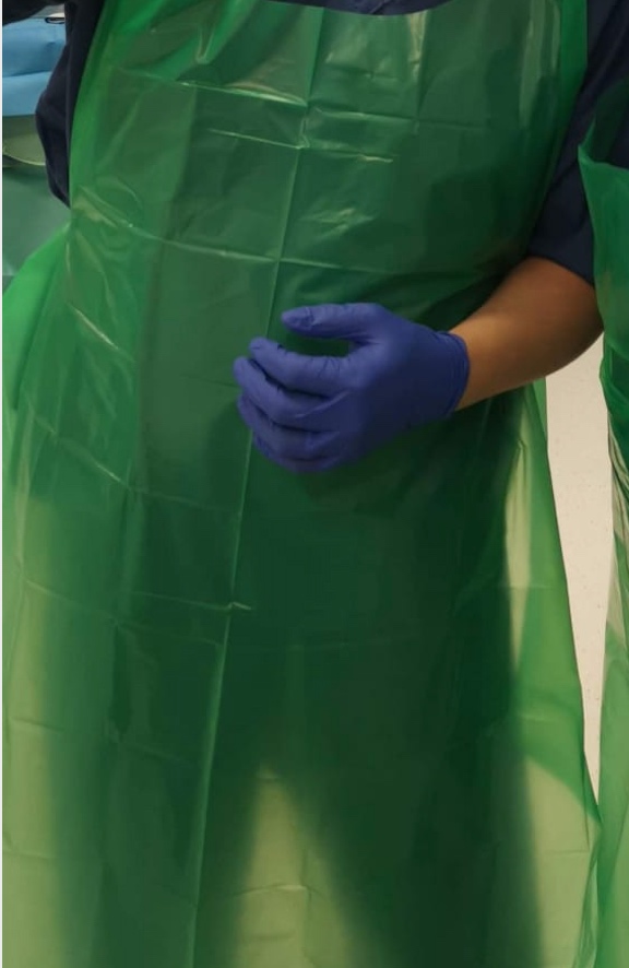 INADEQUATE. A health care staff, not pictured, wears a thin plastic apron for PPE. Medics have complained of inadequate protection. PHE eventually revised their guidelines to require long-sleeved gowns for those dealing with coronavirus patients. 