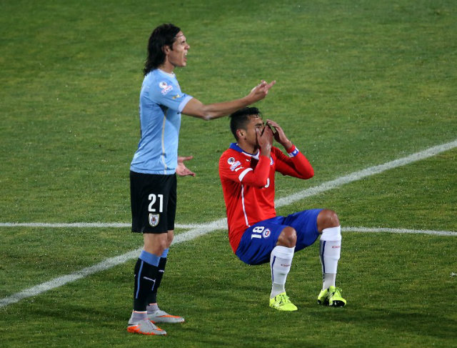 ANY MEANS NECESSARY. Edinson Cavani of Uruguay protests that he was provoked by Gonzalo Jara of Chile to a referee. Photo by Claudio Reyes/AFP 