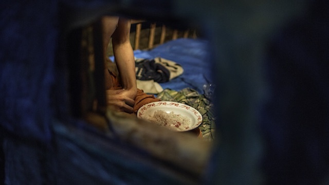 SHACKLED. Ikram, a man with a psychosocial disability, eats his dinner in a shed outside the family home where he has been locked up. His family gives him food and water through a small hole in the shed. Photo by Human Rights Watch