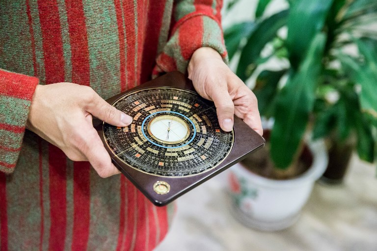 DIVINATION. This picture taken on January 19, 2019 shows feng shui master Alion Yeo holding a luopan, or Chinese compass, in his office in Hong Kong ahead of the Lunar New Year of the Pig. Photo by Isaac Lawrence/AFP  