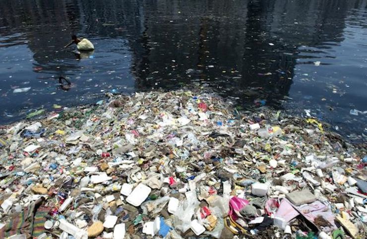 FLOATING TRASH. Aldemar Vallos, 27, collects recycleable plastic in the Pasig River in Manila on June 21, 2014. Noel Celis/AFP
