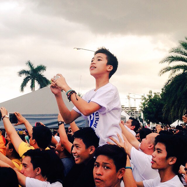 A young boy perches on top of his brother while waiting for the papal motorcade enter the Mall of Asia (MOA) Arena