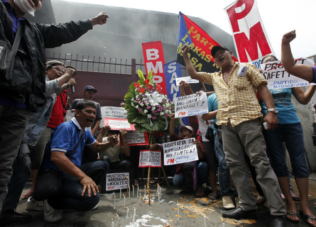PROTEST. Filipino workers offer flowers as they stage a demonstration at the gate of a burnt footwear factory in Valenzuela city, east of Manila, Philippines, May 15 2015. File photo by Francis R. Malasig/EPA 